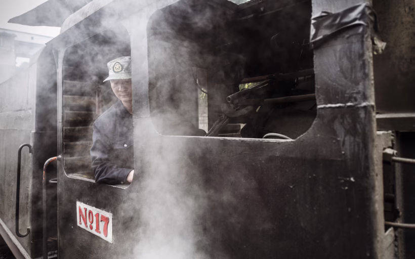 A train conductor peers out of the window