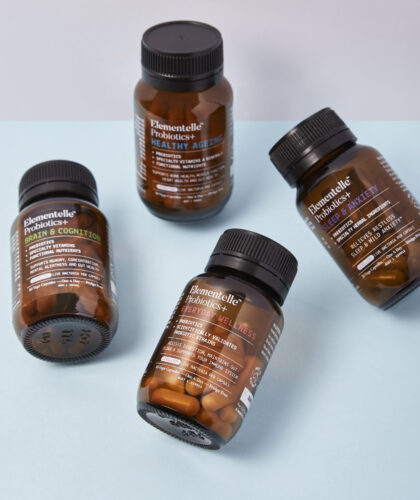 Four bottles of Elementelle Probiotics+ arranged artfully against a light blue background