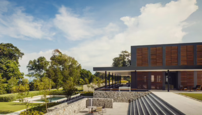 Modern building with wooden accents, stone steps and manicured greenery surrounded by lush tropical landscape at Desaru Coast