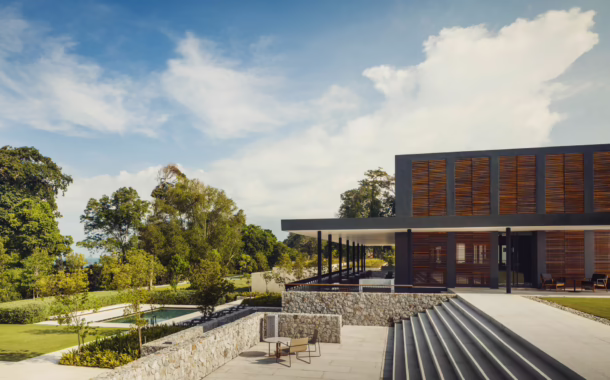 Modern building with wooden accents, stone steps and manicured greenery surrounded by lush tropical landscape at Desaru Coast