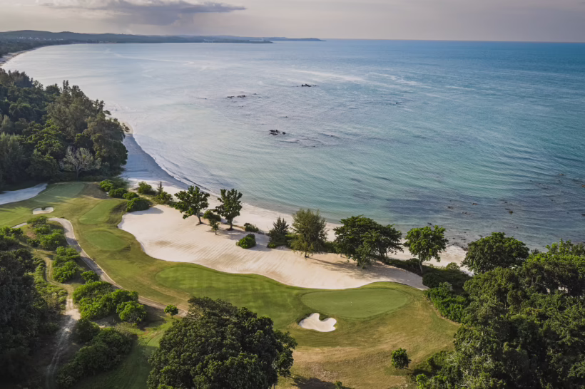 Aerial view of lush coastline and turquoise waters surrounding The Els Club Desaru Coast