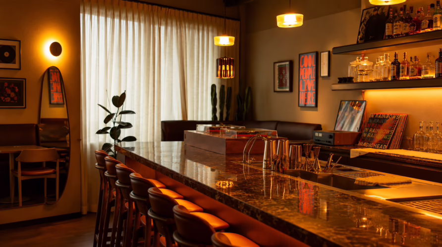 Interior of Toma y Toma cocktail bar in Bangkok with marble bar counter, warm pendant lighting, vinyl records and lounge seating.