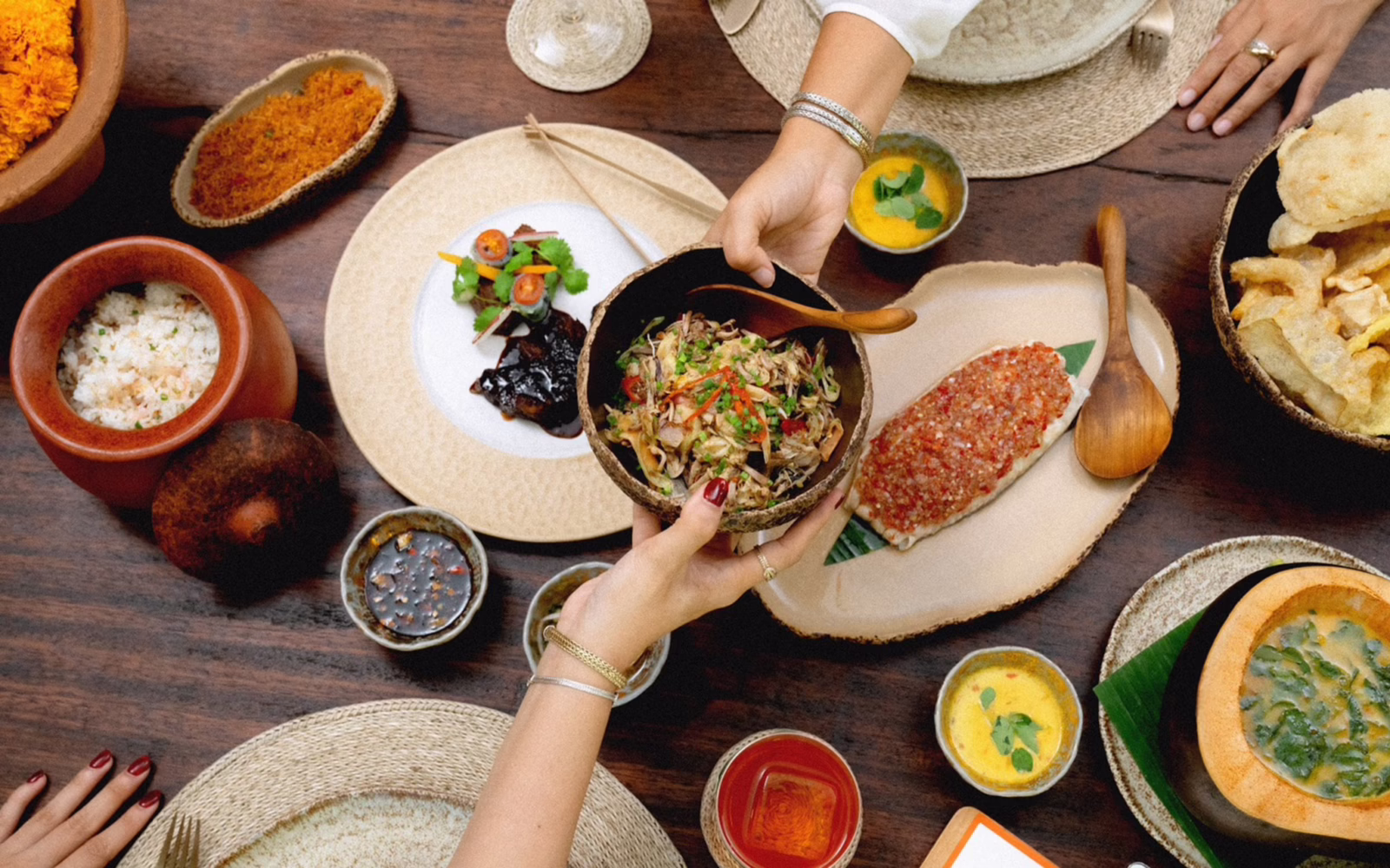People sharing several dishes at The Long Table Restaurant and Bar in Seminyak, Bali.