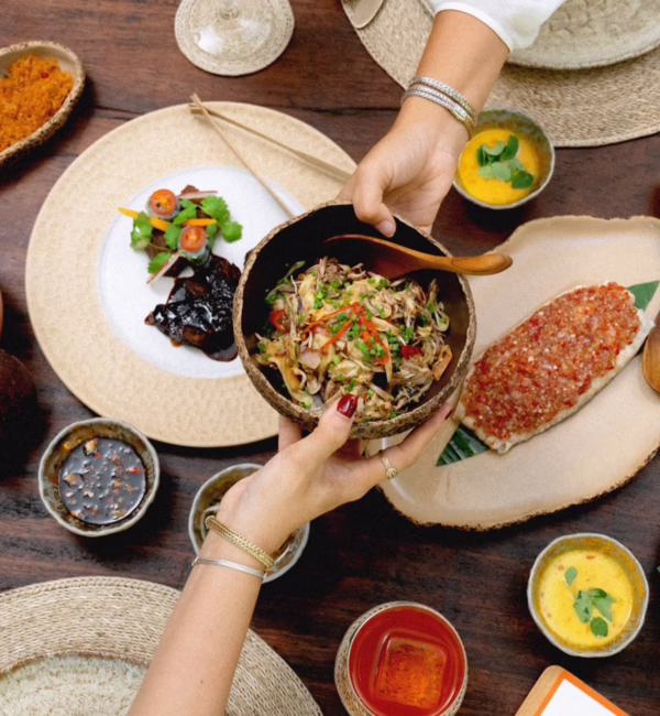 People sharing several dishes at The Long Table Restaurant and Bar in Seminyak, Bali.