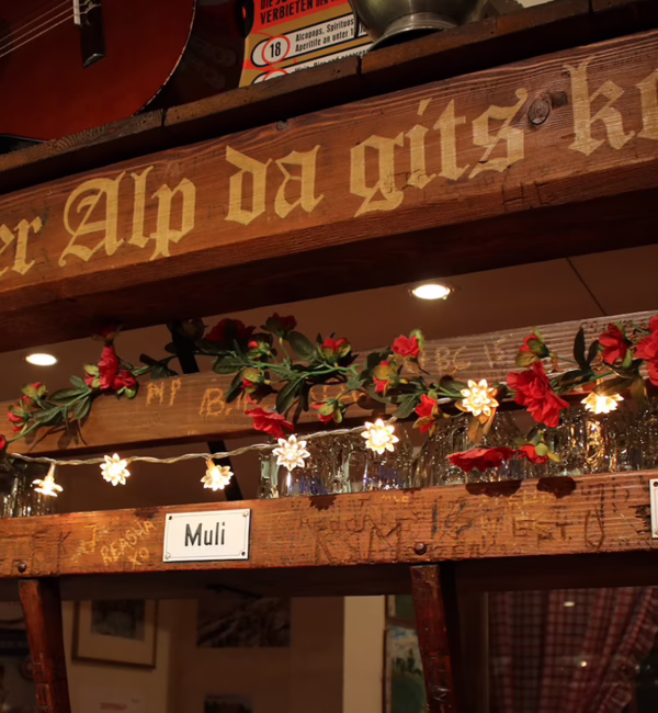 Warm timber-panelled interior of Älpli Bar in Zurich, with wooden tables and traditional décor.