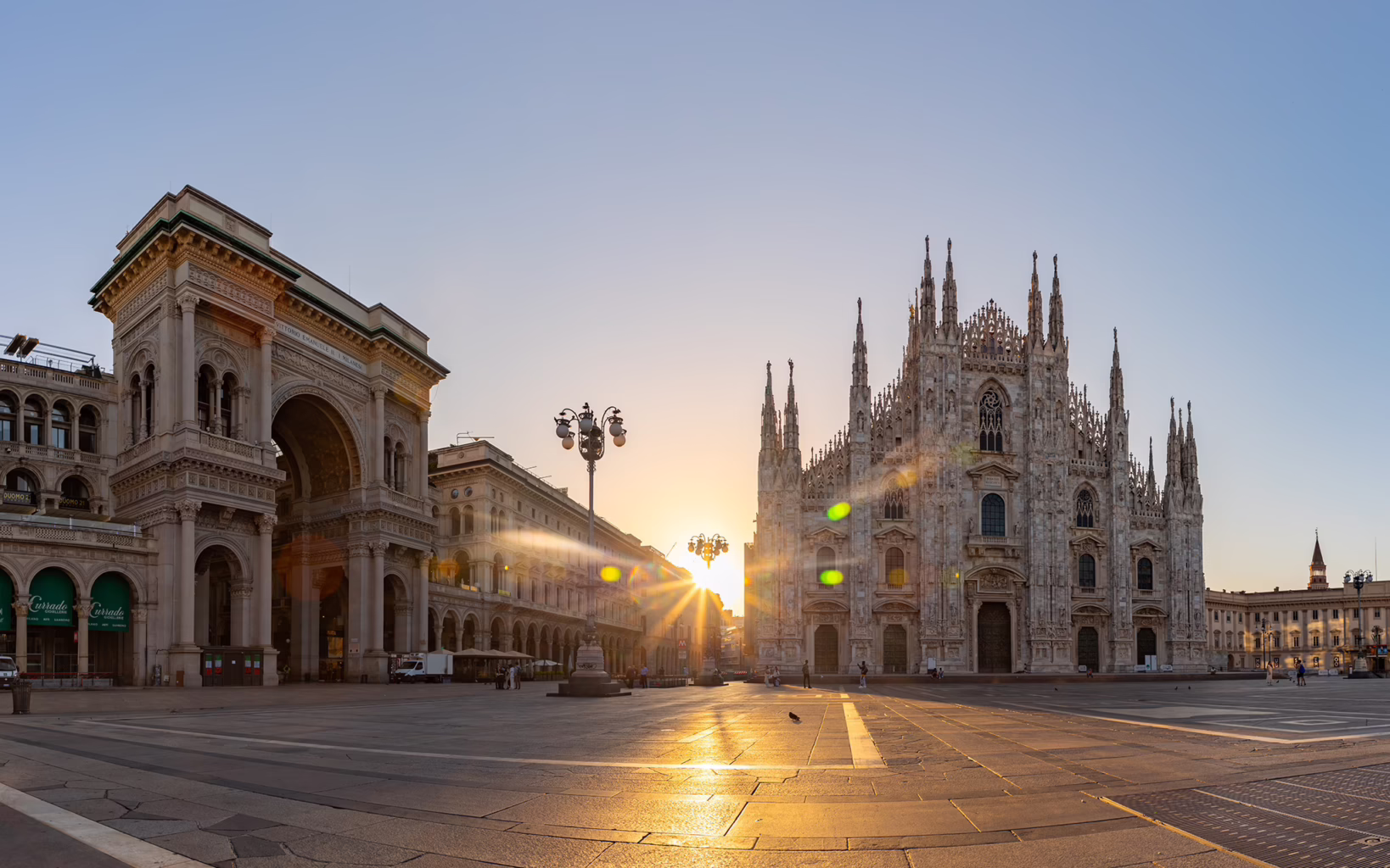 Duomo di Milano and its Gothic spires silhouetted against the sunset sky in Milan, Italy