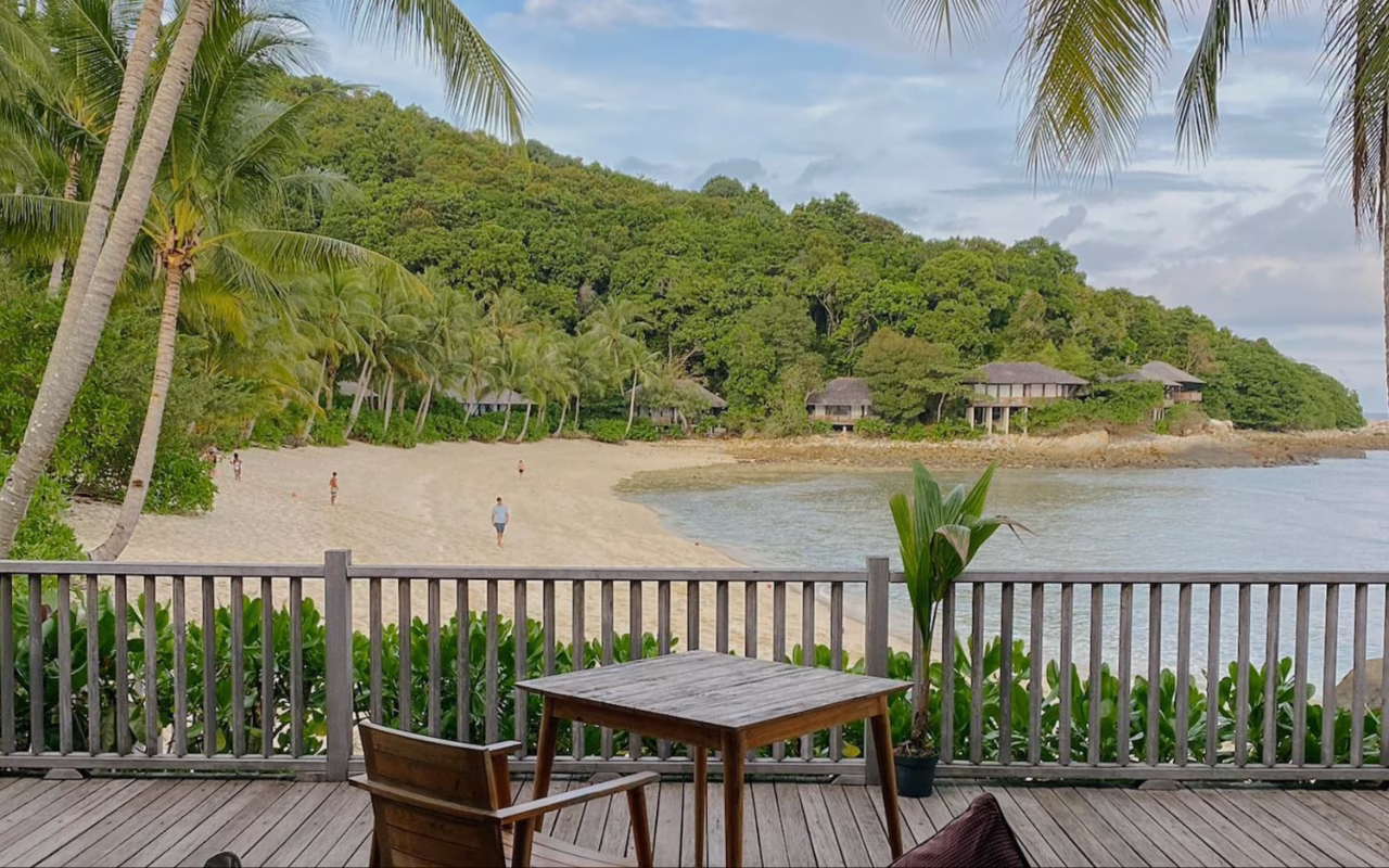View of Pulau Tengah’s forested coastline, sandy beach and clear waters surrounding Batu Batu resort in Johor, Malaysia.