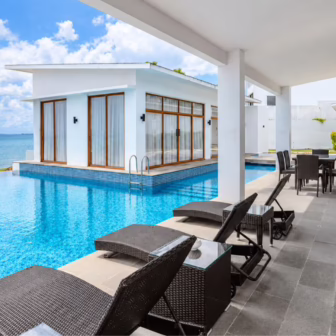 Private infinity pool overlooking the sea at Montigo Resorts Nongsa in Batam, with white villas, sun loungers and an outdoor dining area.