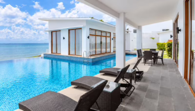 Private infinity pool overlooking the sea at Montigo Resorts Nongsa in Batam, with white villas, sun loungers and an outdoor dining area.