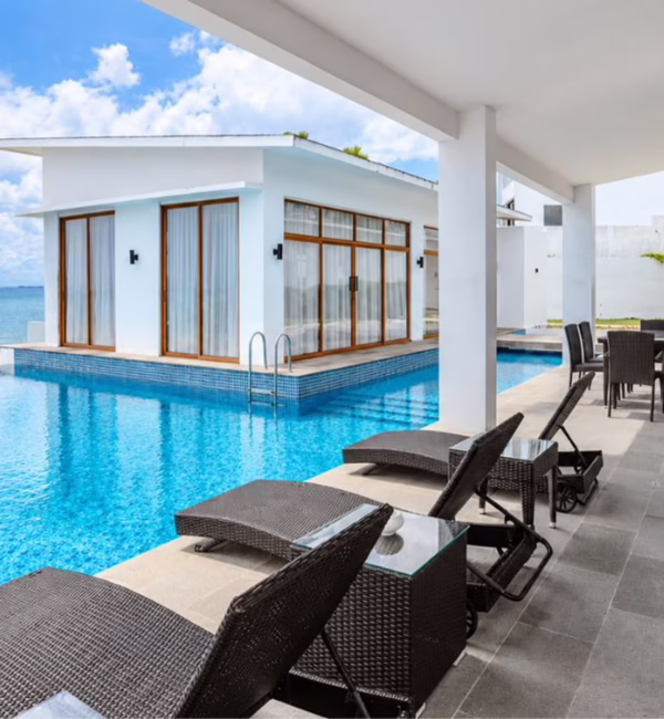 Private infinity pool overlooking the sea at Montigo Resorts Nongsa in Batam, with white villas, sun loungers and an outdoor dining area.