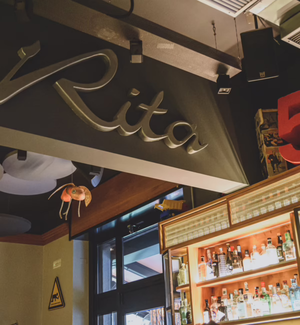 Rita cocktail bar in Milan, featuring its signature signage, illuminated spirits display and a large red number five above the bar.