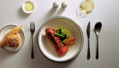 Poached Maine Lobster with Champagne Sauce (Suites and First Class Main Course) features slow-poached Maine lobster shell-on with buttery Savoy cabbage, grilled baby leeks, roasted sweet potatoes, borage cress, and a Champagne cream sauce