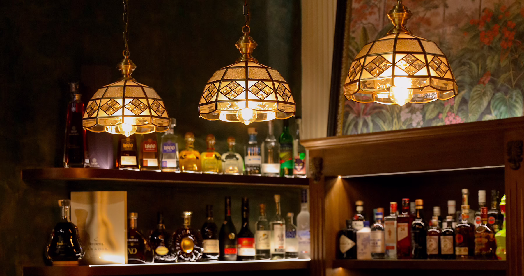 Back bar at Alma Luna Shanghai, with bottles of spirits beneath vintage-style pendant lights.