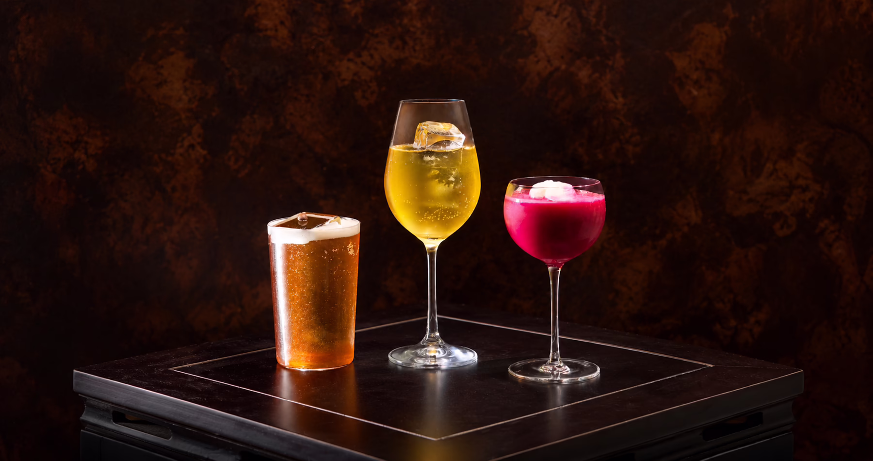 Three colourful cocktails from Asian Flush Shanghai, presented against a dark backdrop.
