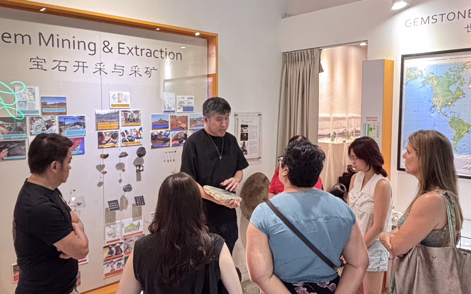 A guide holds up a mineral specimen while explaining gemstone mining and extraction to visitors at The Gem Museum in Singapore.