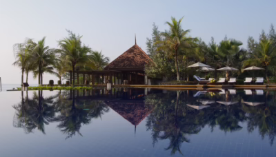 Infinity pool at Tanjong Jara Resort in Terengganu, reflecting a traditional Malay-style pavilion and surrounding palm trees, with sun loungers and umbrellas overlooking the South China Sea.
